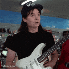 a man wearing a wayne 's world hat is playing a guitar