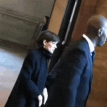 a man and a woman are standing next to each other and shaking hands .