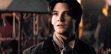 a young man with a scarf around his neck looks to the side