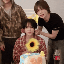 a boy is holding a sunflower in front of a cake that says 20 on it