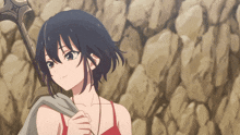 a girl in a red top is holding a sword in front of a rock wall
