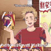 a man in a red shirt is holding a box that says " now on sale " and " he totes loves makanda "