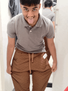 a young man sticking his tongue out while wearing a grey polo shirt