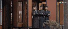three men standing in front of a building with a wetv logo