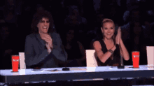 a man and a woman sitting at a table clapping