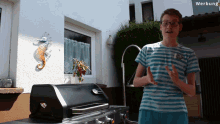 a boy in a striped shirt stands in front of a grill with the word werbung in the background