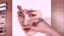 a person is drawing a man 's face with a pencil on a piece of paper