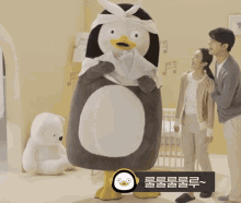 a penguin mascot is standing next to a woman and a man