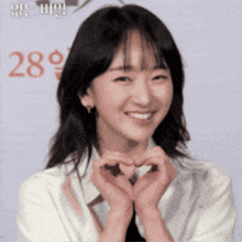 a woman is making a heart shape with her hands
