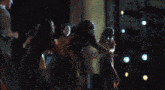 a group of people are dancing in a dark room with lights on