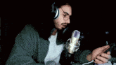 a man wearing headphones and a microphone looks at a cell phone