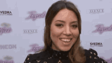 a woman is smiling and waving on a red carpet in front of a sign that says avenue .
