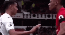 two soccer players are shaking hands on the field during a match .
