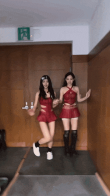 two women are dancing in a hallway with a green exit sign behind them