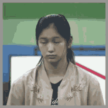 a young girl with her eyes closed is wearing a jacket with flowers on it