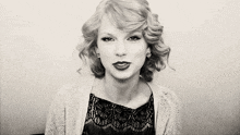 a black and white photo of taylor swift wearing a lace top and a cardigan .