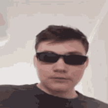 a young man wearing sunglasses and a black shirt .