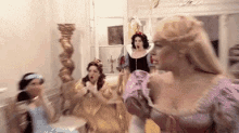 a group of women dressed as princesses are dancing together in a room .