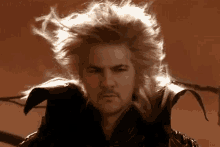 a man with his hair blowing in the wind is wearing a black jacket .