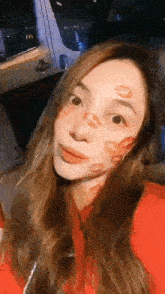 a woman with kisses on her face is taking a selfie in a car .