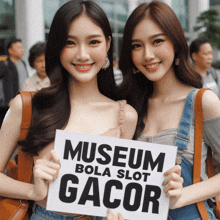 two women are holding a sign that says museum bola slot gacor