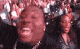 a man is laughing while sitting in front of a crowd of people at a concert .