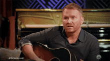 a man playing a guitar on nbc 's songland