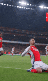 a soccer player in a fly emirates jersey is kneeling down on the field