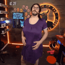 a man in a purple dress is standing in front of a sign that says " manfools "