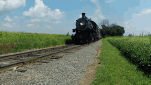 a train is going down the tracks with a field in the background