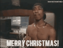 a shirtless man is saying merry christmas while standing in front of a microphone .