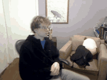 a man in a black jacket is sitting in a chair in front of a picture of a surfboard