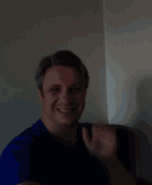 a man in a blue shirt is smiling and waving at the camera