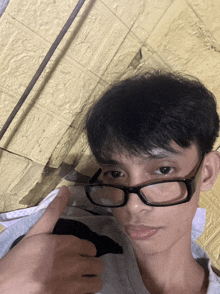 a young man wearing glasses is giving a thumbs up sign