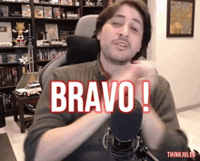 a man sitting in front of a microphone with the word bravo written on the screen