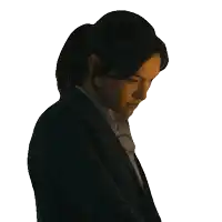 a woman in a suit and ponytail looks down