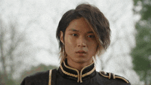 a young man with long hair is wearing a black uniform