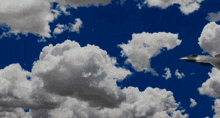 a fighter jet flies through a cloudy blue sky