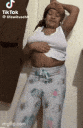 a woman is standing in front of a wall holding her belly .