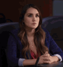 a woman is sitting at a table with her hands folded
