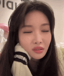 a woman with her eyes closed is wearing a sweater with rhinestones on it