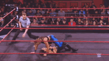 a wrestler is kneeling down in a wrestling ring with the word nxt on the wall