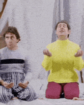 a man in a yellow sweater sits on a bed