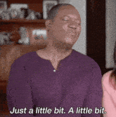 a man in a purple shirt is making a face and saying just a little bit a little bit