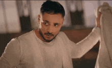 a man with a beard is wearing a white shirt that says ' calvin klein ' on it