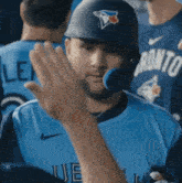 a man wearing a blue jays jersey is giving a high five to another man