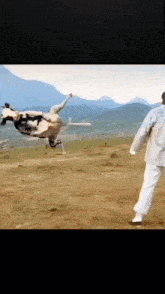 a cow is flying through the air in a field while a man watches .