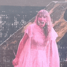a woman in a pink dress is standing on a stage with a microphone in her hand .