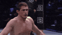 a shirtless fighter stands in front of a dazn sign