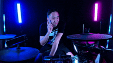 a man wearing a black shirt with the number 7 on it is playing drums